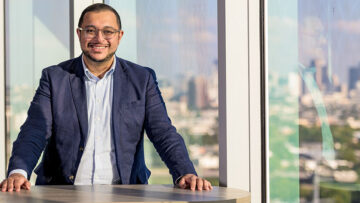 IMAGE: CurveBiosciences founder, Ritish Patnaik, standing at a table with the Dallas skyline behind him.